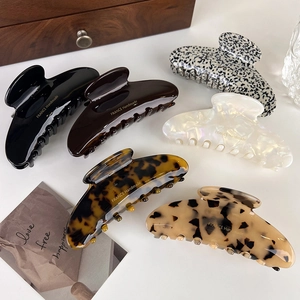 Detail showing six acetate hair claws in black, tortoiseshell and pearl white finishes