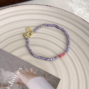 Vue macro de perles en cristal violet avec breloque cœur dorée sur une assiette en céramique