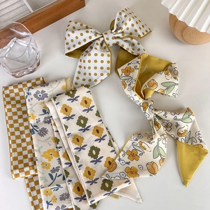 Detailed flat lay of mustard yellow floral and polka dot silk scarves on a white desk