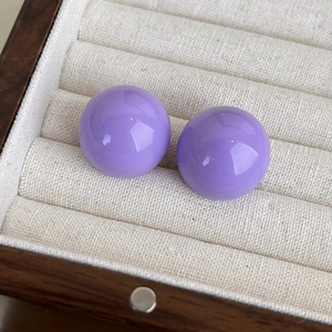 Vista dettagliata dell'orecchino a lobo in resina viola lucida nel suo astuccio beige