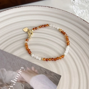 Détails d'un bracelet de perles avec agate orange et un pendentif coeur doré élégant