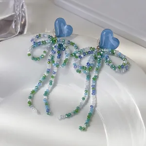 Boucles d'oreilles cœur bleu avec perles de cristal colorées et longs glands sur un plat