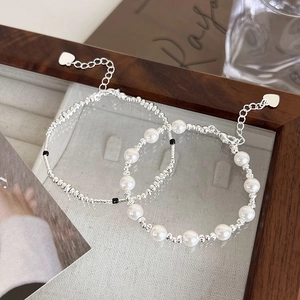 Detail view of retro silver beaded bracelet set with pearls and heart charm on glass tray