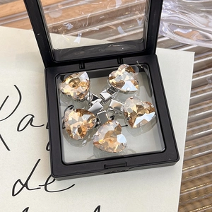 Set of five heart-shaped champagne crystal hair clips displayed in a black storage box