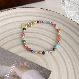 Détail du bracelet en perles colorées facettées avec breloque cœur sur une assiette