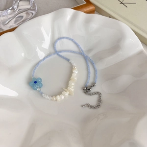 Détail d'un collier de plage avec perles bleues, perles d'eau douce et pendentif fleur