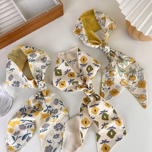Detailed view of three floral silk scarves in yellow and grey for hair and bag styling