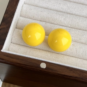 Dettaglio di orecchini a lobo a sfera gialli in resina color caramella in un portagioie