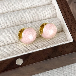 Detailed macro view of French style pink enamel bean earrings with golden metal texture