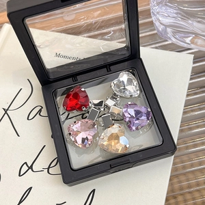Detail view of five multicolored rhinestone heart hair clips in a black display box