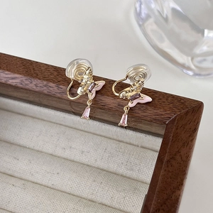 Détail de boucles d'oreilles papillon à clip avec émail rose et pierres violettes