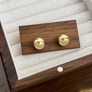 Gros plan de boucles d'oreilles boules dorées sur carte en bois dans une boîte cadeau