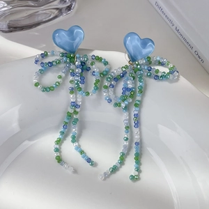 Détail de boucles d'oreilles nœud en perles de cristal bleu avec de longs pompons