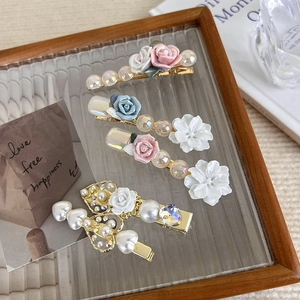 Close-up of five-piece floral and pearl hair clip set on a vintage glass tray