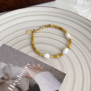 Détail d'un bracelet en pierres jaunes avec perles baroques et pendentif cœur