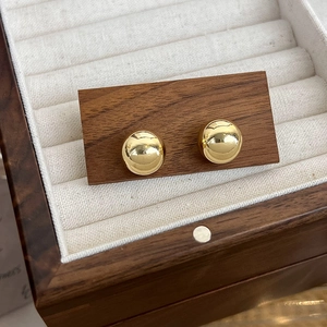 Boucles d'oreilles boules dorées polies dans un écrin à bijoux en bois et velours