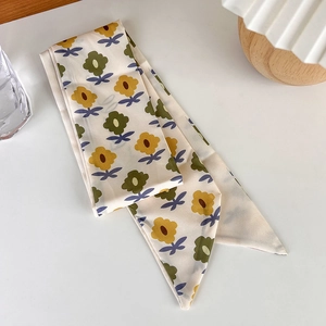 Detailed close-up of yellow and green floral silk twilly scarf used as a bag accessory