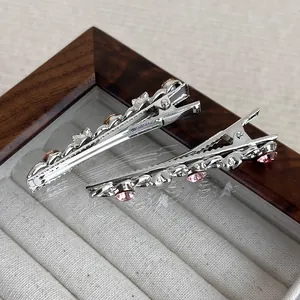 Detailed macro view of silver alloy hair clips with pink rhinestones on velvet lining