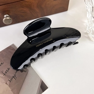 Detail of glossy black acetate hair claw clip with golden France Handmade lettering