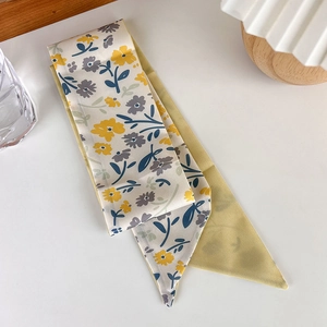 Detail view of a yellow floral skinny silk scarf with pointed ends for hair or bags