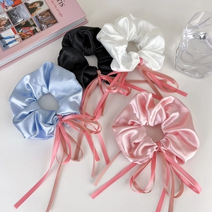 Détail de chouchous en satin avec rubans en bleu clair, noir, blanc et rose
