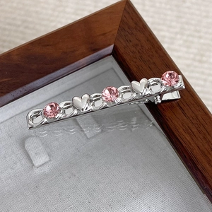 Detailed macro view of the silver chain hair clip with pink rhinestones and heart charms