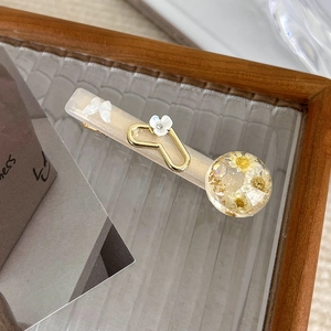 Detail of handmade resin hair clip with white butterfly and heart motif on glass tray