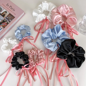 Vue à plat de chouchous en satin avec nœuds en blanc, rose, bleu et noir pour coiffures