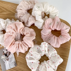 Detalle de coleteros variados de encaje rosa y crema sobre una bandeja de madera