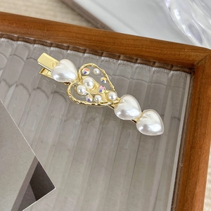 Macro detail of heart-shaped pearls and crystal rhinestones on a gold hair clip