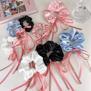 Détail de chouchous en satin de soie avec de longs rubans en rose, bleu, noir et blanc