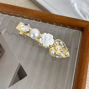Detail of vintage gold hair clip with white resin rose, faux pearl, and hollow heart