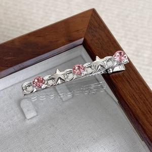 Close-up of silver metal hair clip with pink rhinestones and star-shaped details