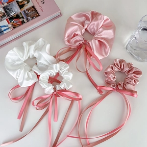 Vue détaillée de chouchous en satin avec de longs rubans en blanc et tons rose pâle