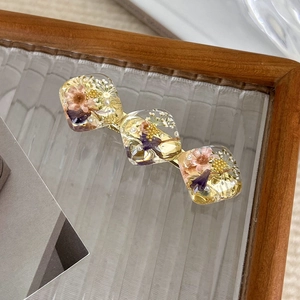 Detail of vintage hair clip with real dried flowers and gold foil embedded in resin