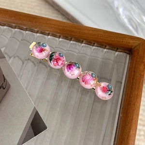 Detail of pink dried flower resin spheres with gold leaf on a vintage hair clip