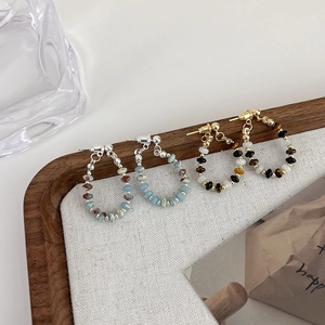 Detail of handmade beaded hoop earrings with natural stone beads on a rustic linen tray