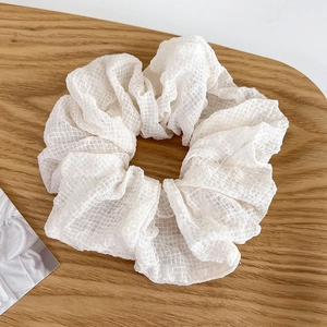 Detalle de coletero de encaje blanco con textura de malla fina sobre madera