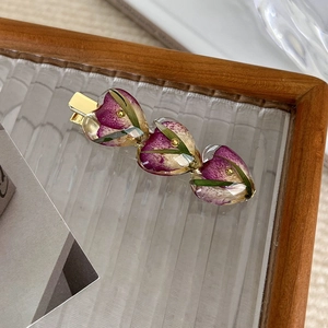 Detail of golden hair clip with three heart resin blocks containing purple dried flowers