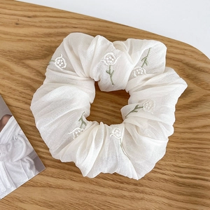 Primer plano de coletero crema con bordado floral blanco y patrones de hojas
