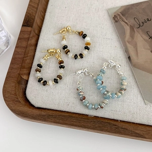 Detail of beaded hoop earrings with natural stone beads on a wooden display tray