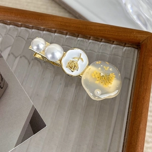 Detail of vintage hair clip with dried flowers, resin and faux pearls on glass tray
