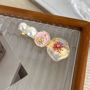 Detail of vintage duckbill clip featuring pink rose cameo pearls and dried flower resin
