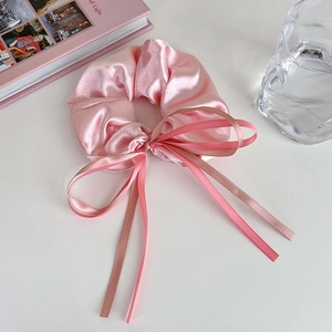 Vue détaillée du chouchou en satin rose avec longs rubans et texture soyeuse