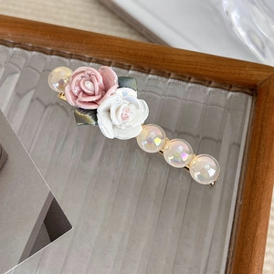 Close-up of pink and white resin roses with iridescent pearls on a gold hair clip