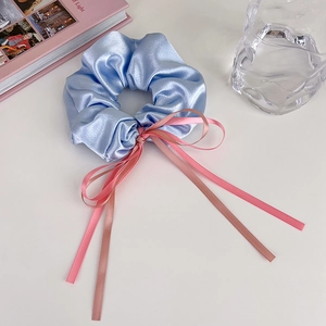 Détail d'un chouchou en satin bleu clair avec un nœud en ruban rose sur table