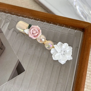 Detail of pink resin rose and iridescent pearls on a vintage gold-toned hair clip