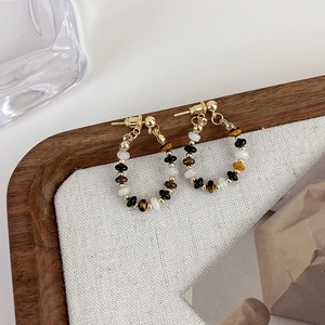 Detail view of vintage stone beaded hoop earrings on a wooden tray with tiger eye stones