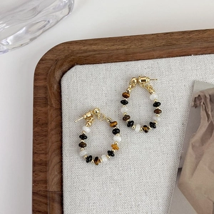 Detail shot of vintage beaded hoop earrings with tiger eye and dark stones on linen cloth