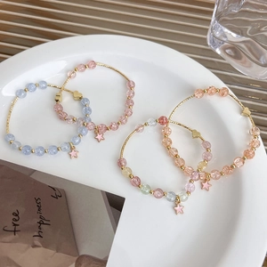 Detailed view of four beaded bracelets with gold metal bars and pink star pendants